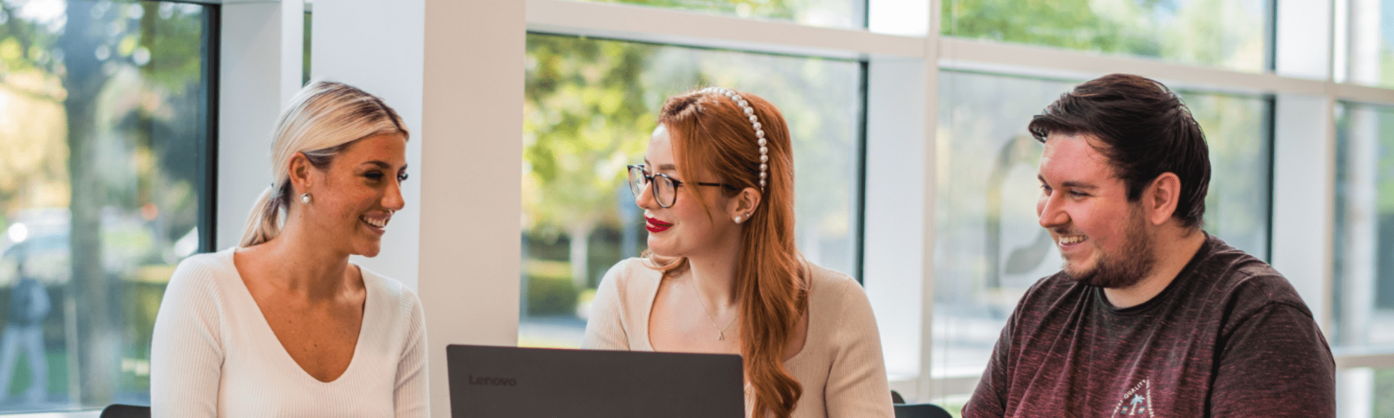 one person leaning over someone working at their desk